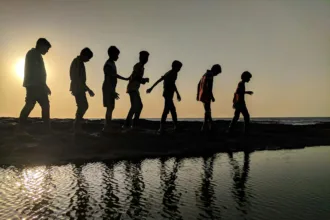group of children walking near body of water silhouette photography