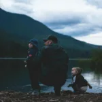 a father and his kids near body of water