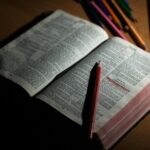 pink pencil on open bible page and pink