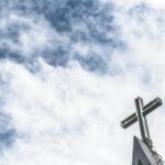 low angle photo of cross under cloudy sky
