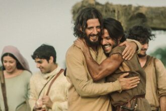 An image of two men hugging in front of others; they're portraying Jesus and Peter in Dallas Jenkins "The Chosen"
