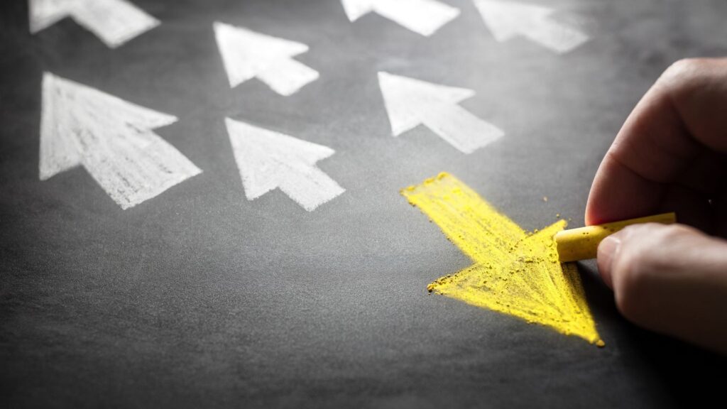 An image of many white arrows going in one direction, and a yellow chalk arrow going in the opposite direction. This is cultural Christianity.