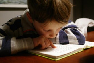 A child reading a book at a wooden table