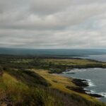 A coastal road beneath heavy clouds, illustrating travel conditions during Kauai’s hurricane recovery