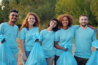 A diverse group of volunteers holding cleanup bags outdoors