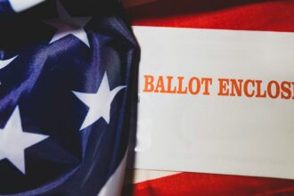 A mail-in ballot form displayed over an American flag.
