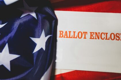 A mail-in ballot form displayed over an American flag.