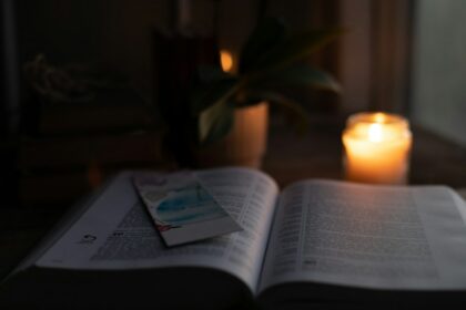 An open Bible illuminated by warm candlelight
