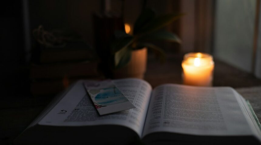 An open Bible illuminated by warm candlelight