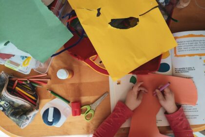 Child creating an art project at a table with colorful craft supplies