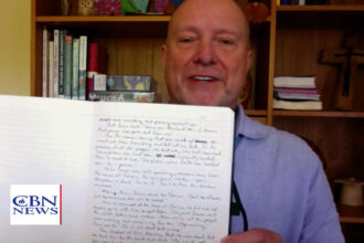 Don Ashley with handwritten New Testament journals during a CBN News interview