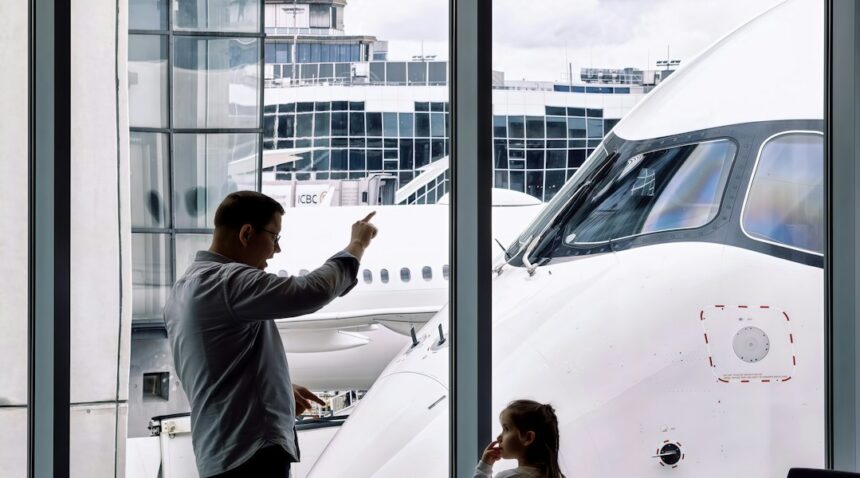 Family looking at an airplane through an airport terminal window