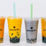 Four colorful boba tea drinks with tapioca pearls and straws