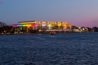 Kennedy Center illuminated at night beside the Potomac River in Washington