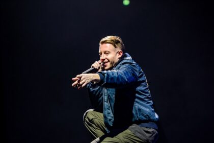 Macklemore performing onstage during a concert