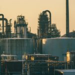 Oil refinery and storage tanks under a golden sky