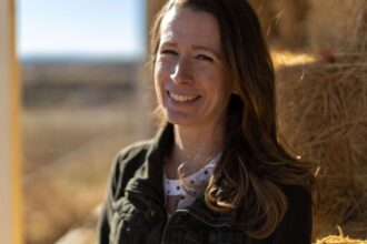 Oregon mother Jessica Bates smiling beside hay bales at her home in Malheur County.