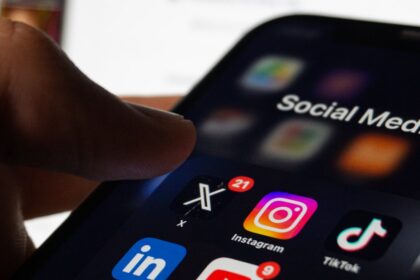Person holding a smartphone displaying social media apps