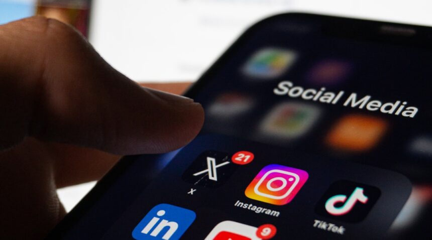 Person holding a smartphone displaying social media apps