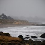 Stormy ocean waves along a misty California coastline