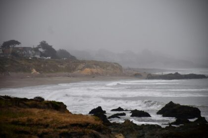 Stormy ocean waves along a misty California coastline