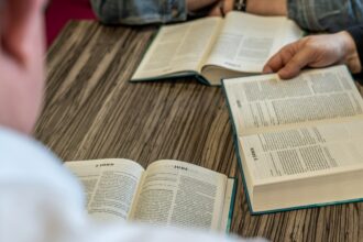 Two people read open books together at a church table.