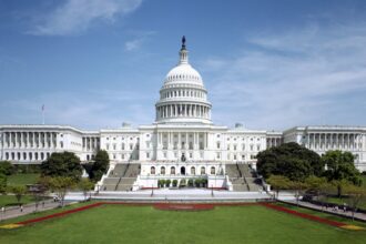 West front of the United States Capitol beneath a blue sky.