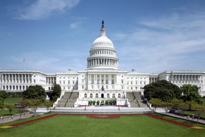 West front of the United States Capitol beneath a blue sky.