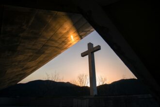 White cross at sunrise illustrating the death and resurrection of Jesus Christ