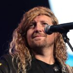Worship leader Sean Feucht performs with a microphone and guitar at a public event in Phoenix.