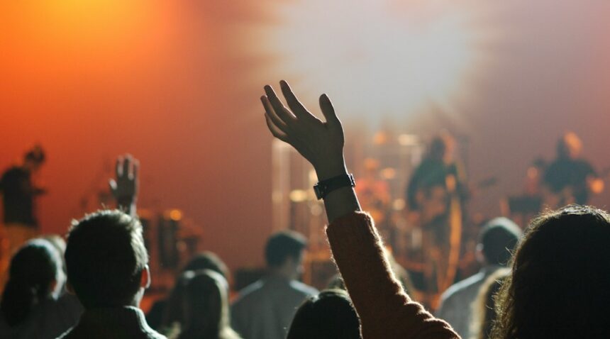 Young adults worshiping together with hands raised