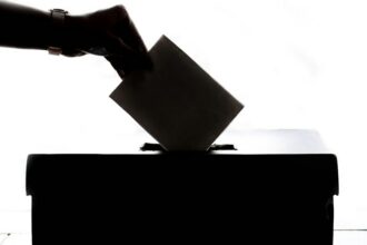 A person placing a ballot into a ballot box. Illustrative photograph.