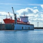 Cargo vessel at an industrial waterfront; illustrative photograph, not the planned Anduril facility