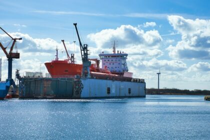 Cargo vessel at an industrial waterfront; illustrative photograph, not the planned Anduril facility