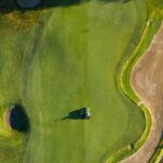 Illustrative aerial photograph of a golf green and bunker; not Newport Beach Country Club.