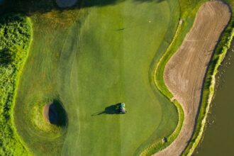 Illustrative aerial photograph of a golf green and bunker; not Newport Beach Country Club.